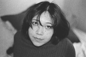 Cinematic black and white classroom portrait of a student sitting alone under dramatic window light